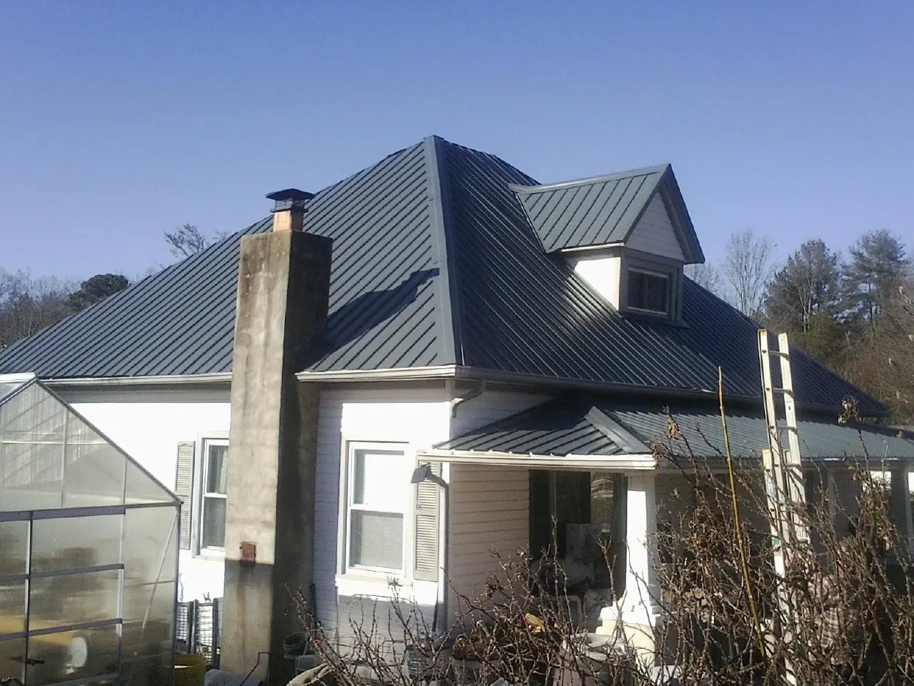 Dark blue standing seam metal roof on a white farmhouse with dormer — Slate & Tile Roof Repair by Roofing Brothers in Troutville